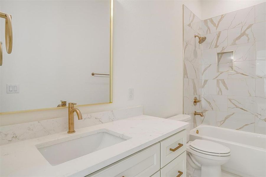 Full bathroom featuring vanity, tiled shower / bath, and toilet