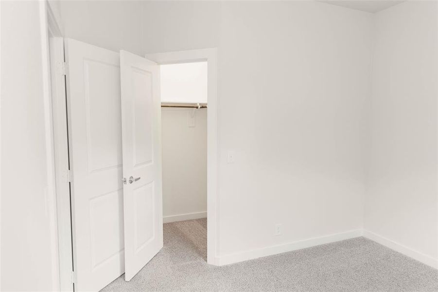 Unfurnished bedroom with a closet, light colored carpet, and a spacious closet