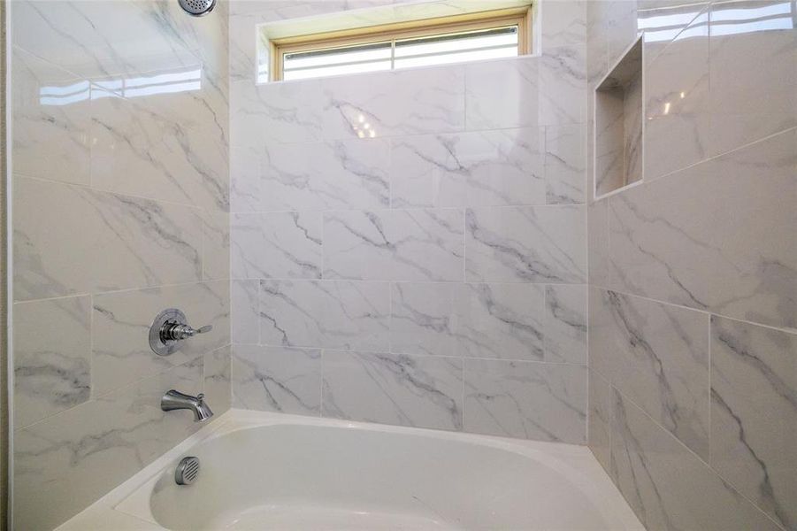 Bathroom featuring tiled shower / bath and a healthy amount of sunlight