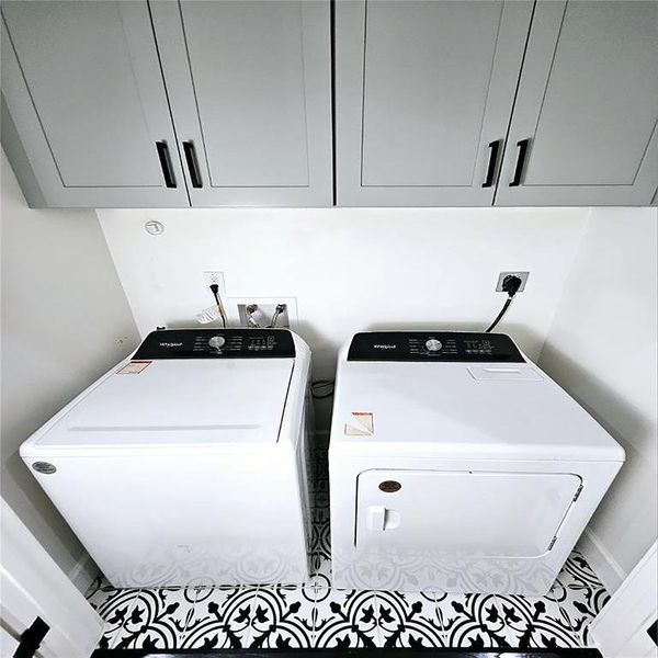 Laundry room has large overhead cabinets.