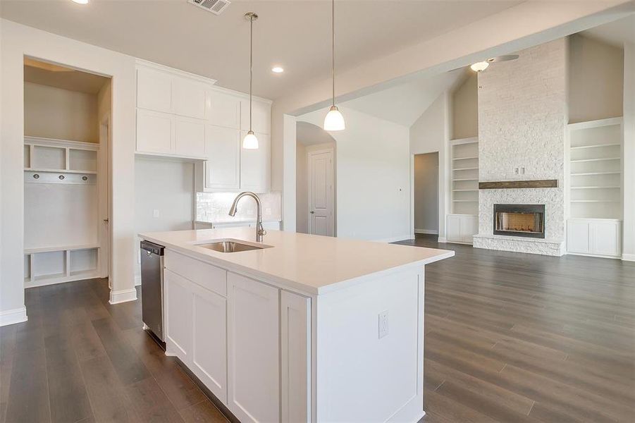 Kitchen featuring built in features, dark hardwood / wood-style flooring, a stone fireplace, and hanging light fixtures