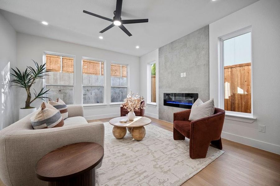 Living room featuring hardwood / wood-style floors, a healthy amount of sunlight, a tile fireplace, and ceiling fan