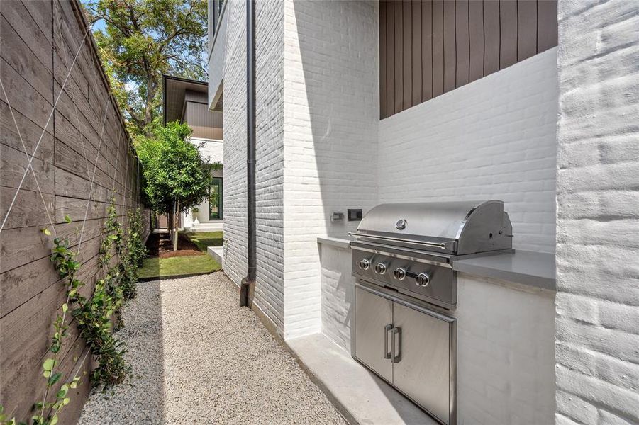 A well-appointed summer kitchen, located off the side of the house, offers a built-in grilling station ideal for outdoor cooking and entertaining and is conveniently just steps away from the side yard making it the perfect set up for entertaining.