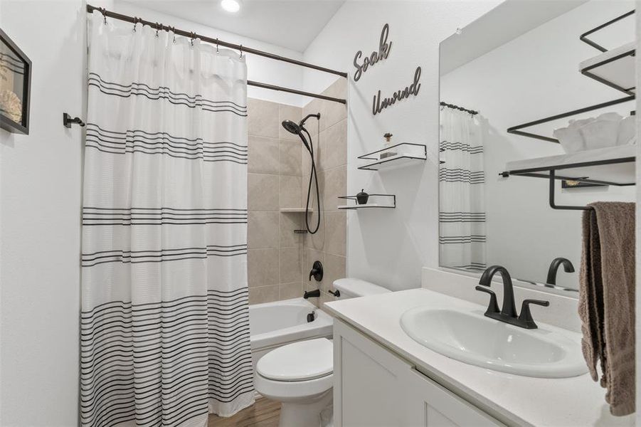 Full bathroom with shower / bath combination with curtain, vanity, and toilet