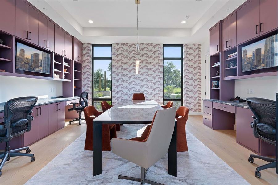 A wall of glass windows and glass doors opens into this luxury home office with space for a large conference room table and built-in desk areas. This space could be repurposed into formal dining and more.