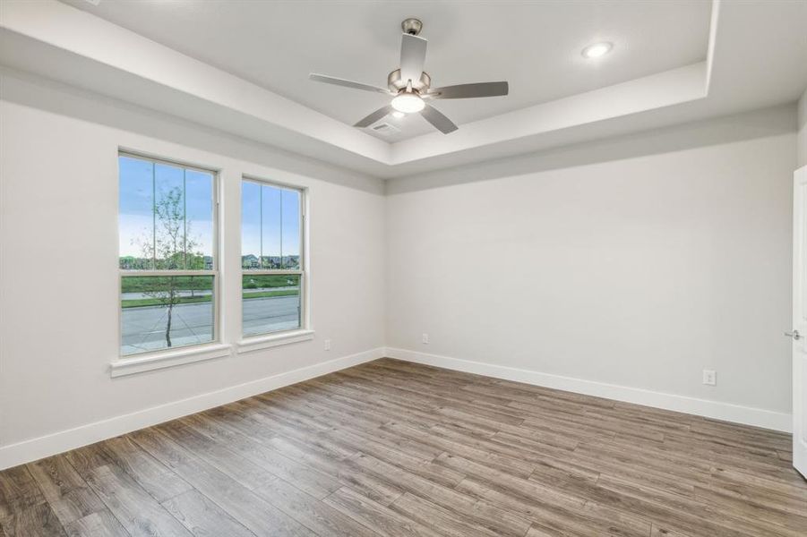 Spare room featuring a tray ceiling, hardwood / wood-style floors, and ceiling fan