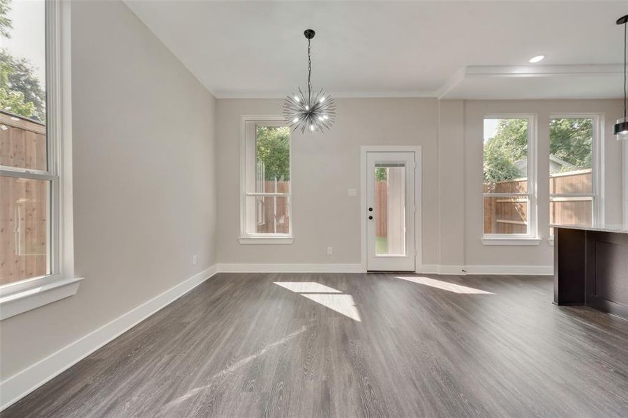 Unfurnished dining area with an inviting chandelier, dark hardwood / wood-style flooring, and ornamental molding