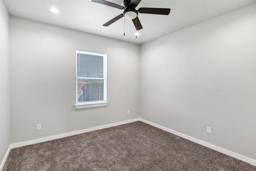 Carpeted spare room featuring ceiling fan