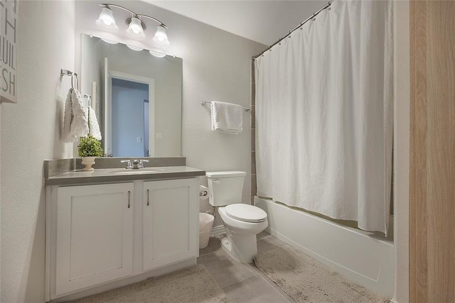 Full bathroom with shower / bath combo with shower curtain, toilet, vanity, and tile patterned flooring