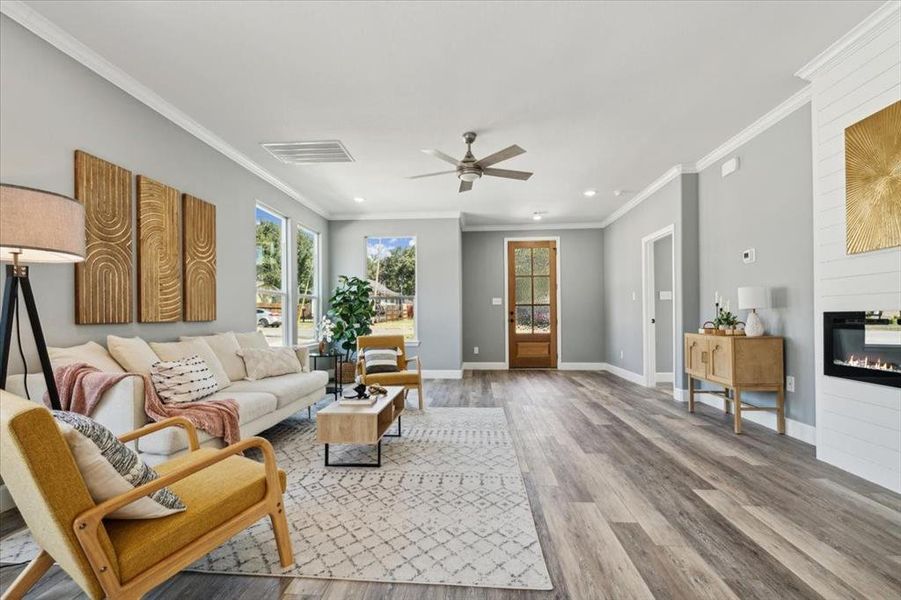 Living room with ceiling fan, hardwood / wood-style flooring, plenty of natural light, and crown molding