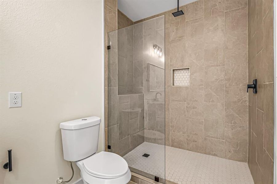 Walk in shower with seamless glass shower panel and tile accent inlay.