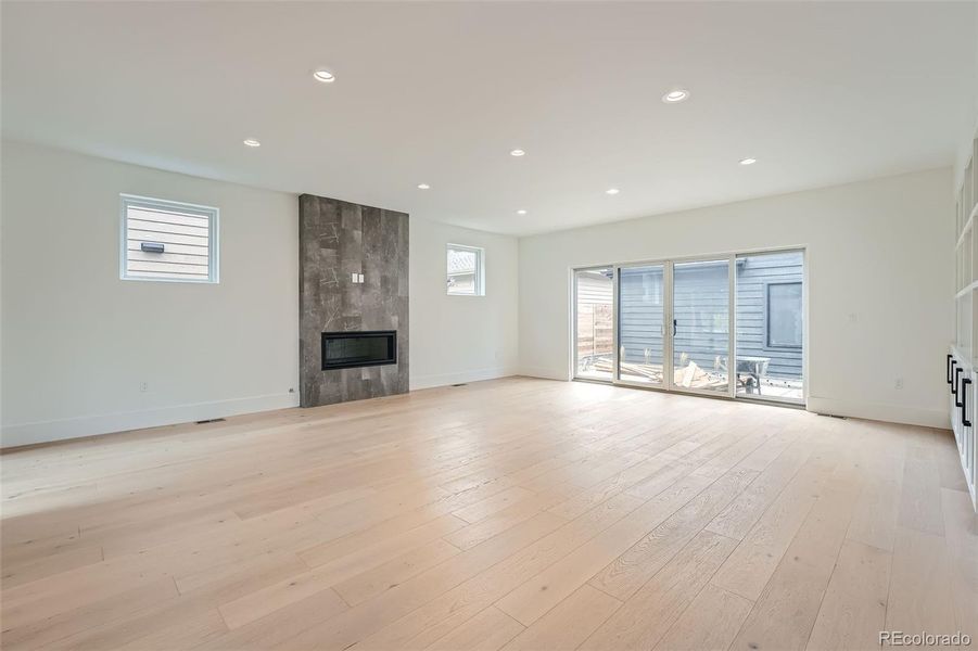 Expansive great room centered around a linear fireplace accent wall while seamlessly transitioning to dual outdoor spaces creating an inviting indoor-outdoor living experience.