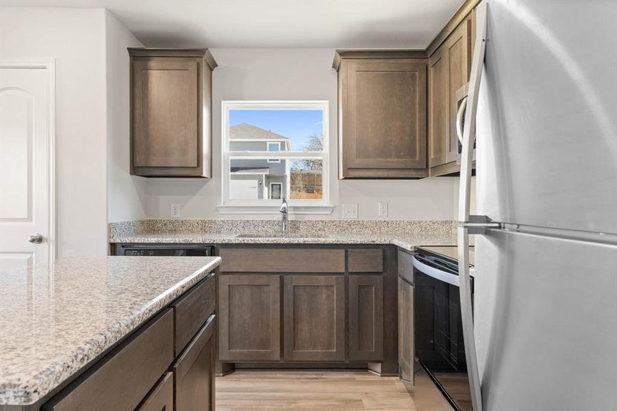 Kitchen featuring light stone counters, sink, black / electric stove, white refrigerator, and light hardwood / wood-style floors