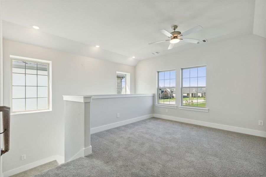 Carpeted spare room with lofted ceiling and ceiling fan