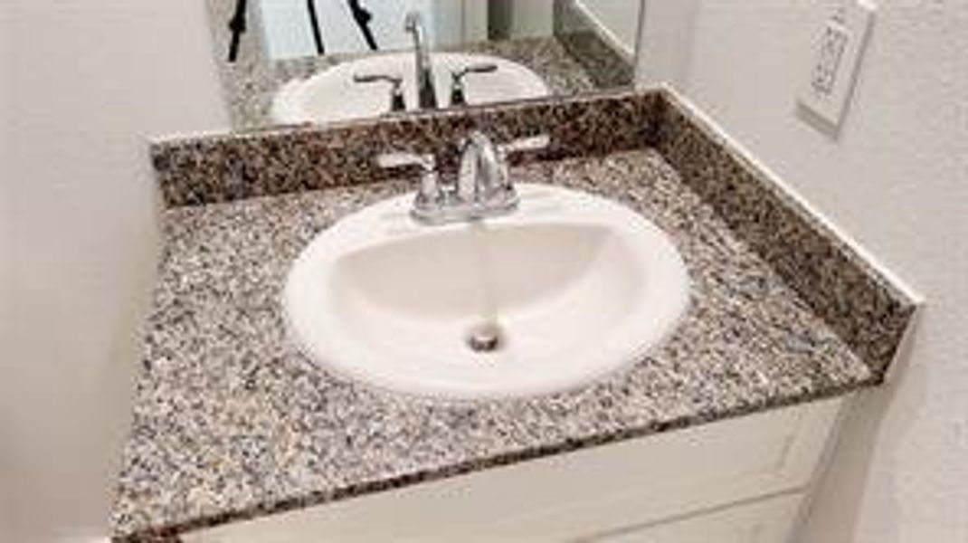 Elegant granite countertop with modern sink and sleek faucet in a pristine bathroom setting.