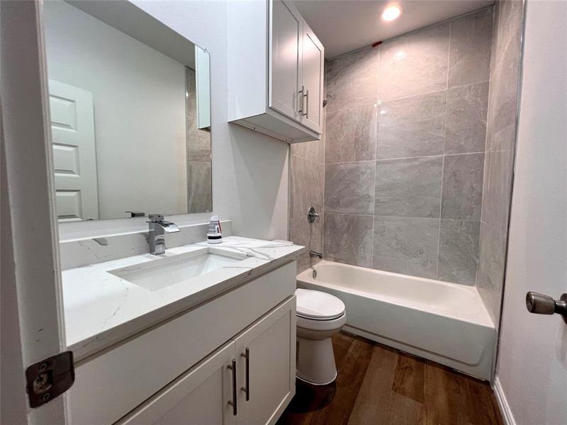 Full second bathroom featuring shower / bath combo, hardwood / wood-style floors, toilet, and vanity with extensive cabinet space