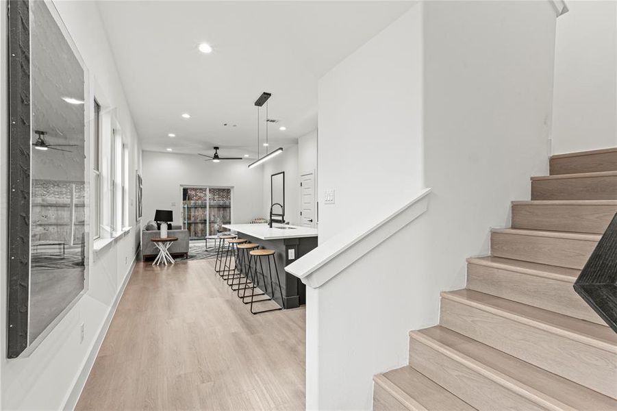 Stairs with wood-type flooring, ceiling fan, and sink