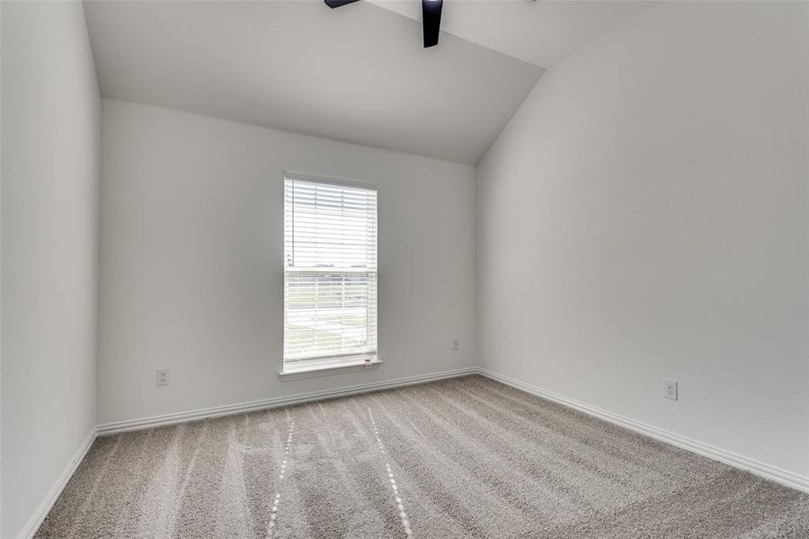 Carpeted spare room with ceiling fan and lofted ceiling