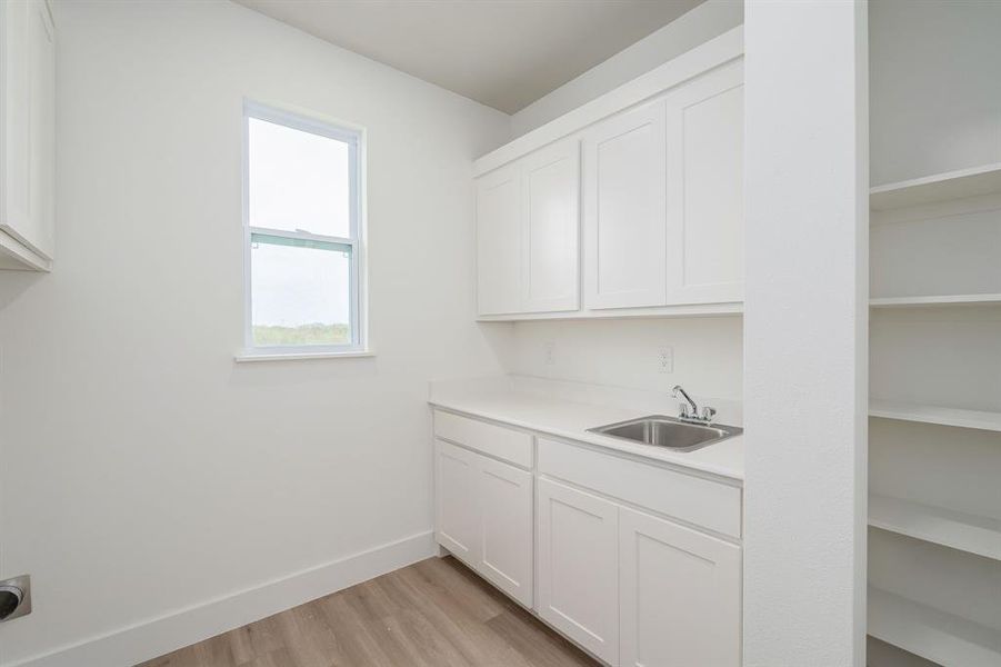 Laundry area featuring light wood-type flooring, cabinets, and sink