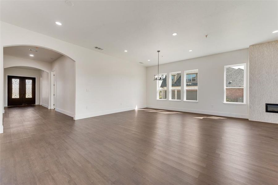 Unfurnished living room featuring a notable chandelier, a healthy amount of sunlight, and dark wood-type flooring