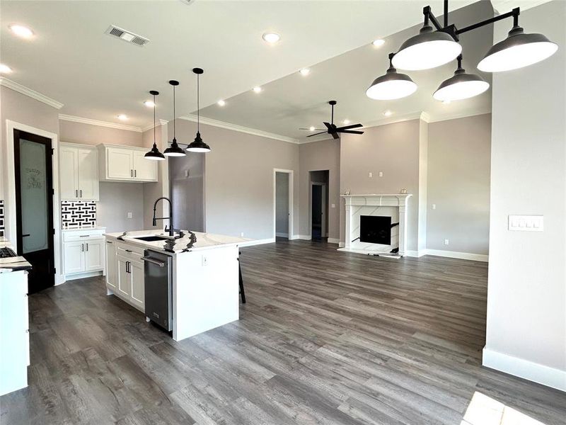 Kitchen with an island with sink, decorative light fixtures, sink, and white cabinetry