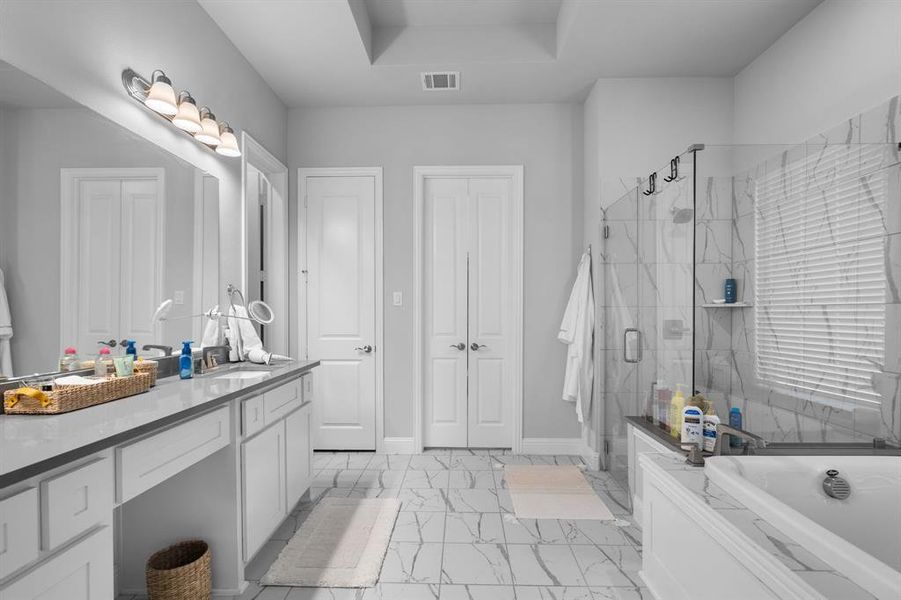 Primary Bathroom with large vanity, a tray ceiling, deep soaker tub and walk in shower