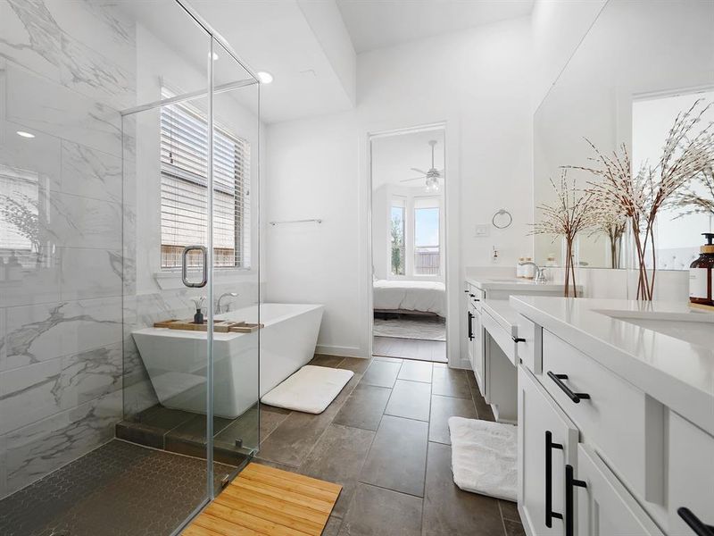 Experience luxury in this spa-like ensuite bathroom, complete with a relaxing soaking tub, elegant frameless shower, dual sinks, and a stylish vanity area with seating for ultimate comfort and convenience.