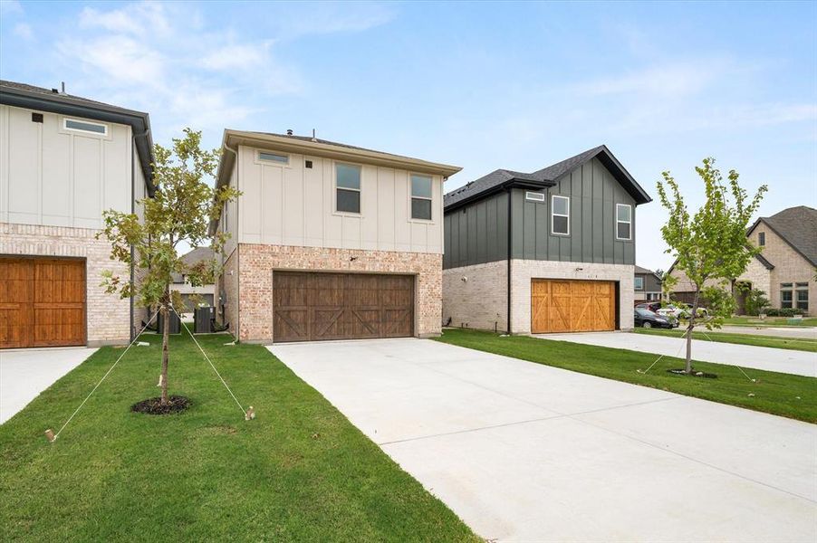 View of front of property with cooling unit, a garage, and a front lawn