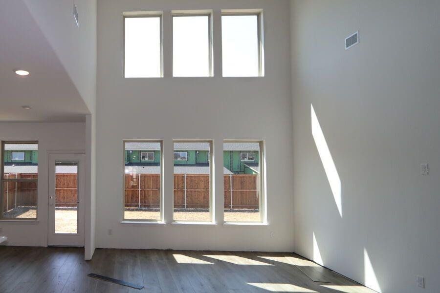 Unfurnished living room featuring hardwood / wood-style flooring and a towering ceiling