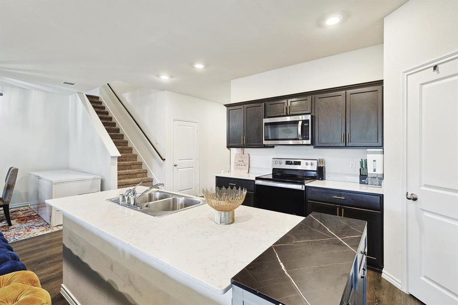 Kitchen with a kitchen island with sink, sink, stainless steel appliances, and dark hardwood / wood-style flooring