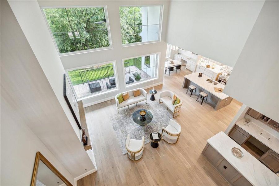 This photo showcases a spacious, modern open-plan living area with high ceilings and large windows that provide plenty of natural light. The living space is elegantly furnished and seamlessly connects to a well-appointed kitchen and dining area, offering a cohesive space for comfortable living and entertaining.