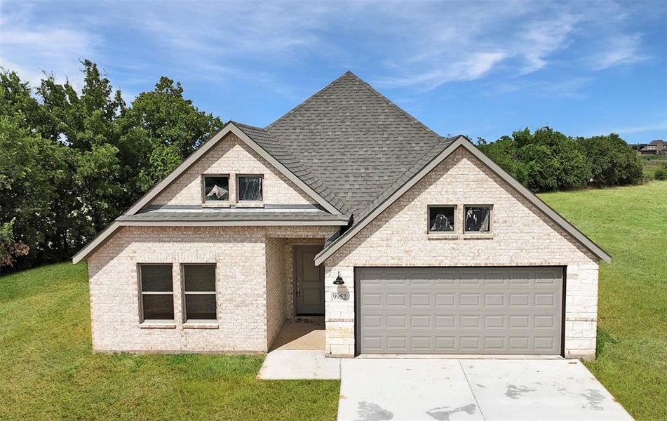 View of front of house featuring a garage and a front lawn