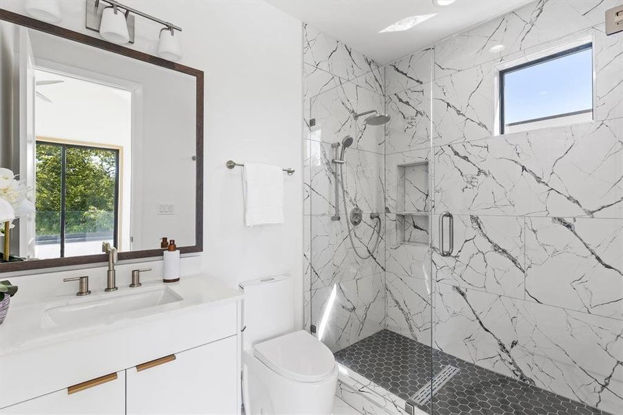 Bathroom with a wealth of natural light, vanity, toilet, and an enclosed shower