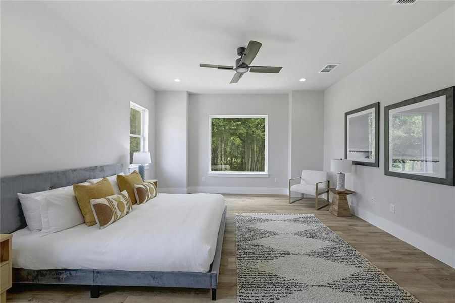 The primary bedroom with large bay windows overlooking the wooded area.