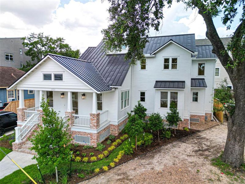 Welcome to 2721 Morrison, only one of its kind in The Woodland Heights! A charming white house with a metal roof, lush greenery, and elegant design.