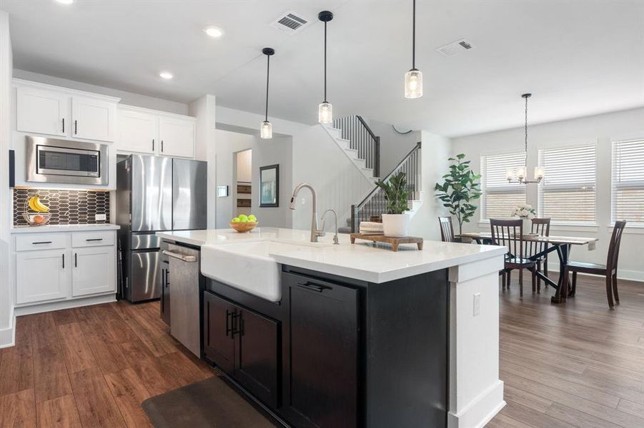 The gourmet kitchen features an upgraded porcelain farmhouse sink and sheek black and white cabinets.