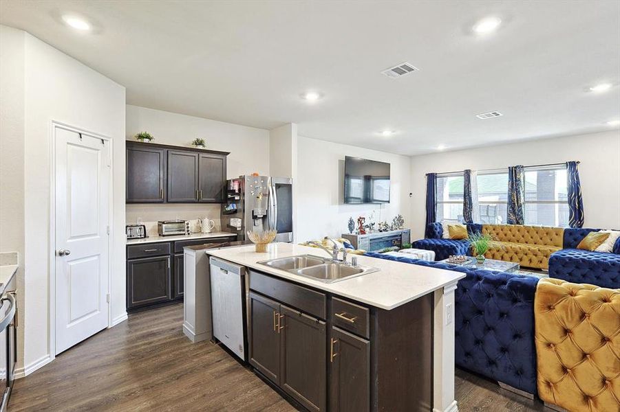 Kitchen featuring an island with sink, dark hardwood / wood-style flooring, stainless steel appliances, dark brown cabinets, and sink