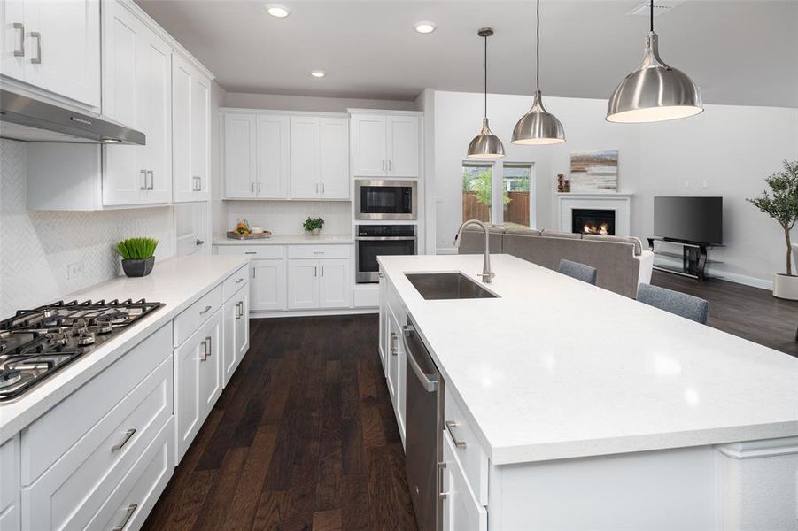 Kitchen featuring white cabinets, appliances with stainless steel finishes, sink, dark hardwood / wood-style floors, and a kitchen island with sink