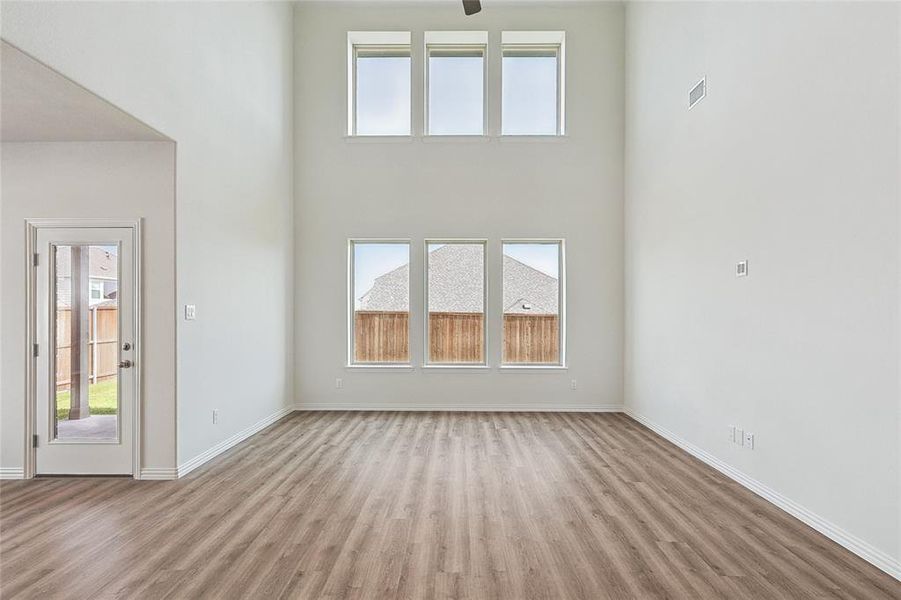 Unfurnished living room featuring a high ceiling and hardwood / wood-style flooring