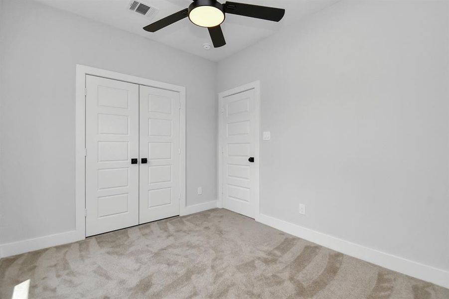 This photo of the third bedroom shows the closet doors which lead to the wall-length closet - this home has so much to offer, and we love that the five-panel doors with beautiful door hardware are found throughout for design consistency!