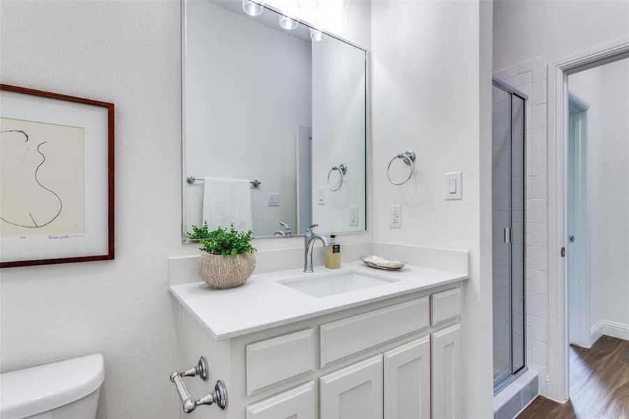 Bathroom with a shower with door, vanity, toilet, and wood-type flooring