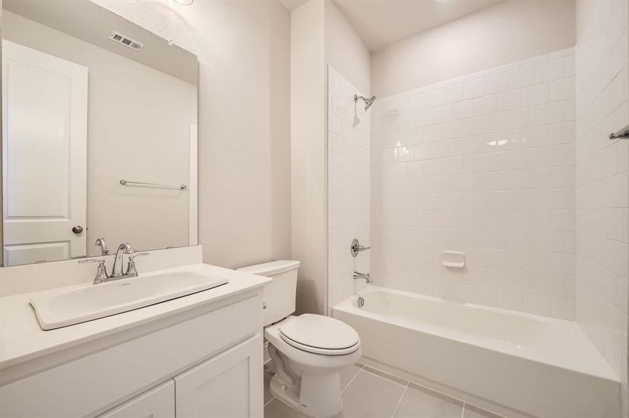 Full bathroom with tiled shower / bath, vanity, toilet, and tile patterned floors