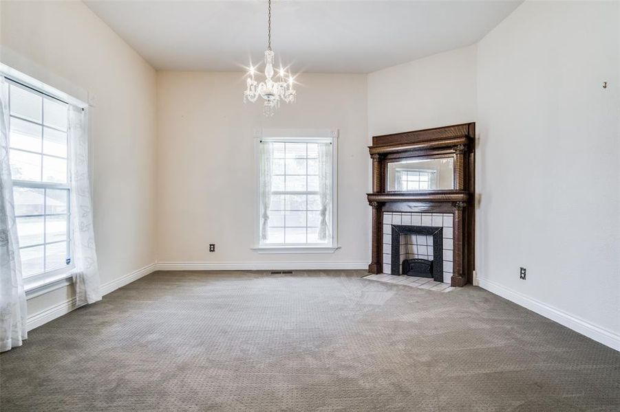 Unfurnished living room featuring carpet floors, a notable chandelier, and a wealth of natural light