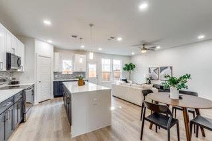 Kitchen featuring range, decorative light fixtures, decorative backsplash, light wood-type flooring, and white cabinetry