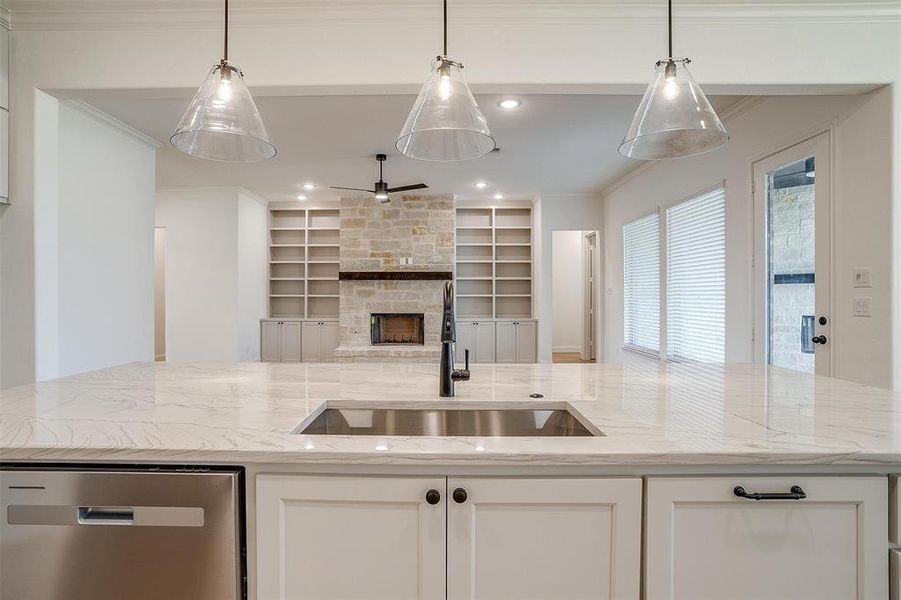 Kitchen with built in features, a stone fireplace, sink, white cabinetry, and dishwasher