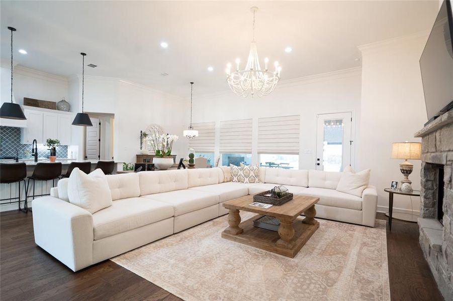 Living room featuring a notable chandelier, hardwood / wood-style flooring, a fireplace, and crown molding