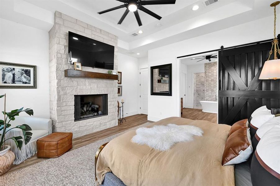 Stone fireplace in primary bedroom with barn doors leading to primary bathroom.