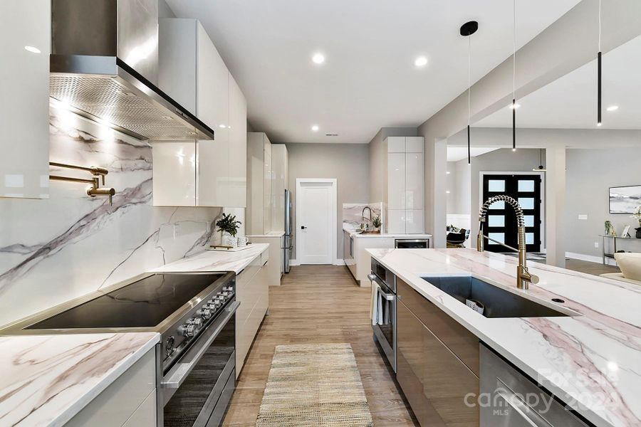 Chef's Kitchen features quartz counters, oversized island with seating/storage, 2 sinks, stainless steel appliances including 2 ovens, dishwasher & separate dishwasher drawer, Refrigerator to remain, amazing, modern cabinetry, modern, custom lighting & induction cook top!