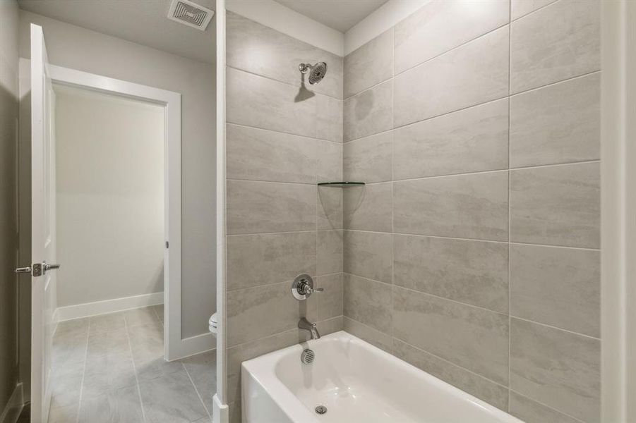 Bathroom featuring tiled shower / bath and toilet