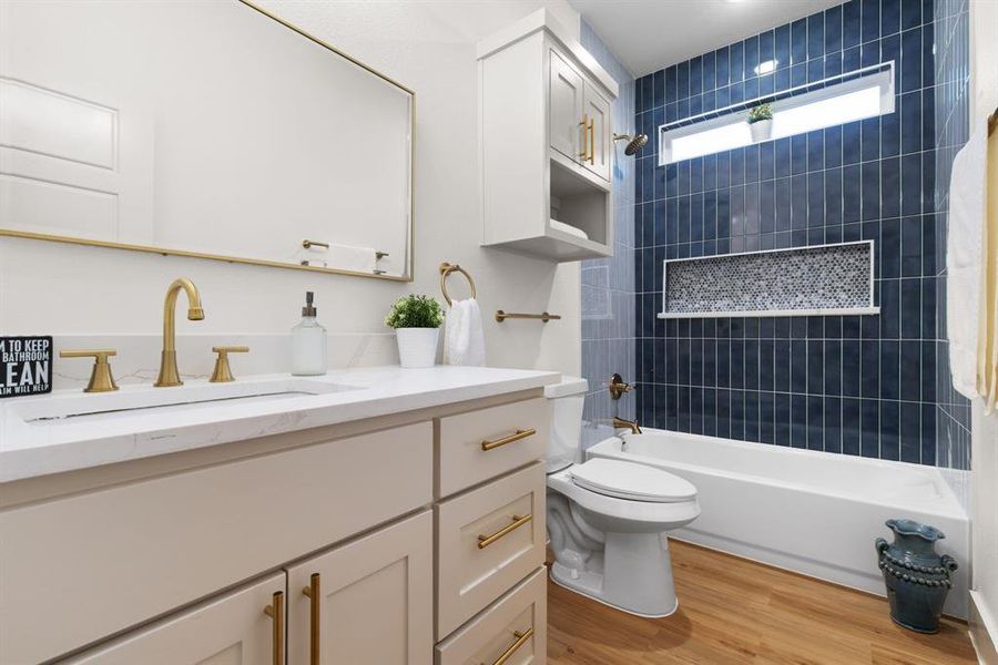 Full bathroom with wood-type flooring, tiled shower / bath, vanity, and toilet